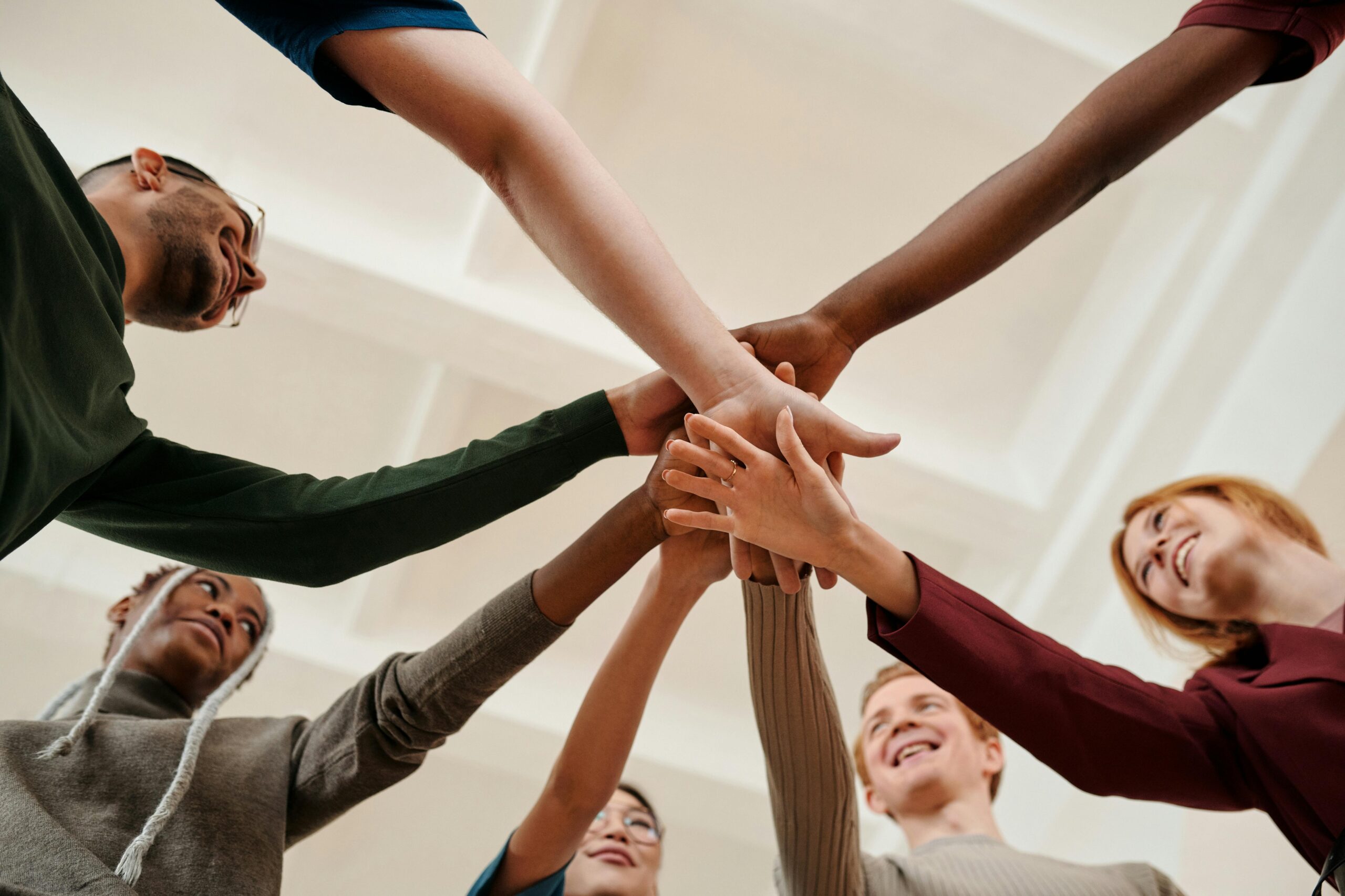a circle of 6 people with their hands all brought to the center